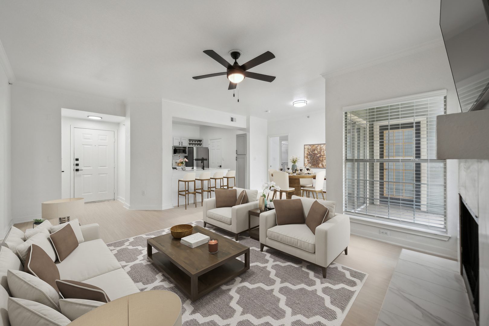 a living room with a ceiling fan and white walls at The Stetson