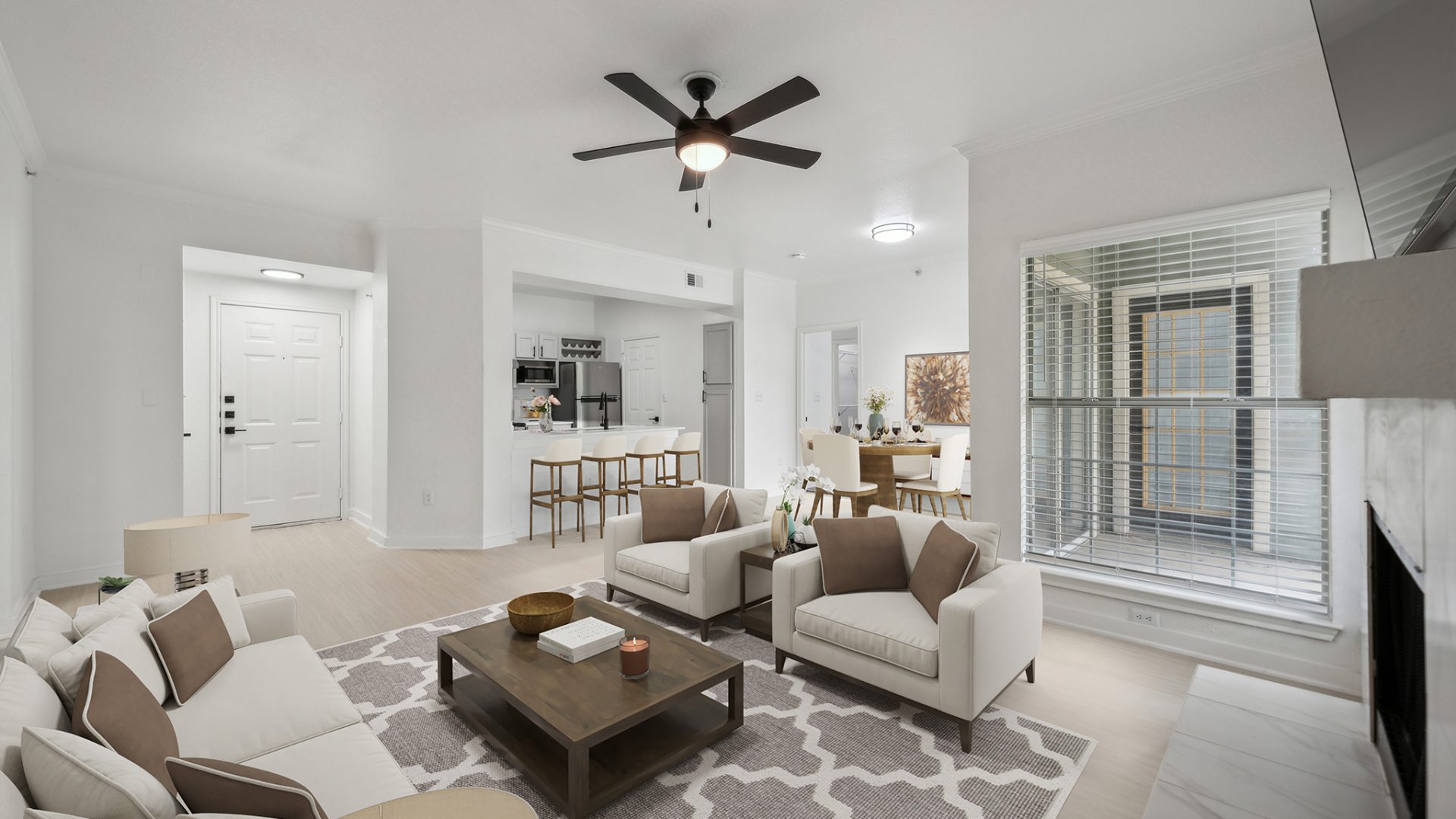 a living room with a ceiling fan and white walls at The Stetson